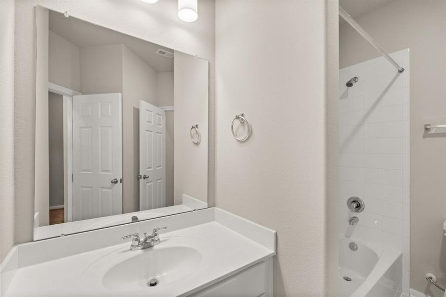 The secondary bath features tile flooring, white cabinetry and light countertops and a shower/tub combo. Perfect for accommodating any visiting family and friends.