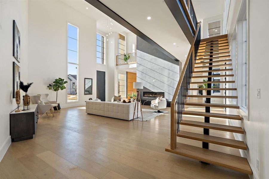 Stairs featuring hardwood / wood-style floors, a towering ceiling, and a healthy amount of sunlight