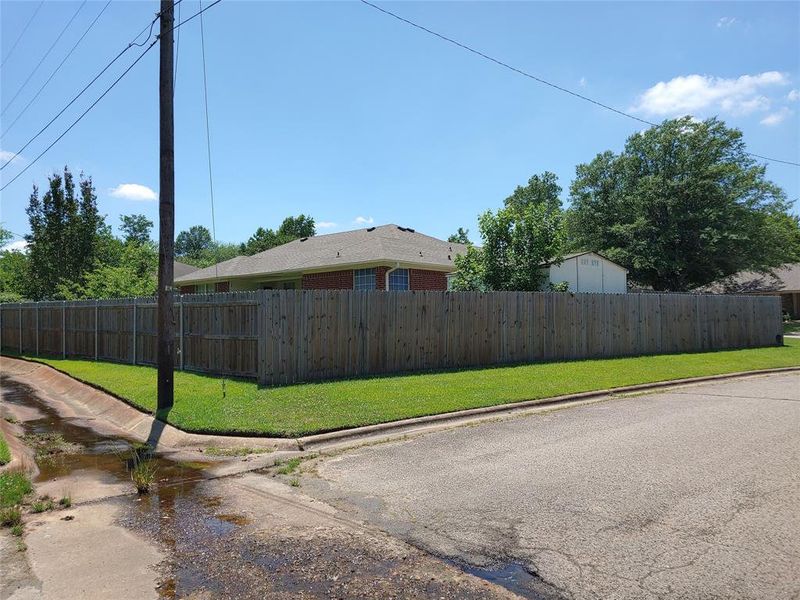 Corner lot with wood privacy fencing, mature trees, and a well-maintained lawn