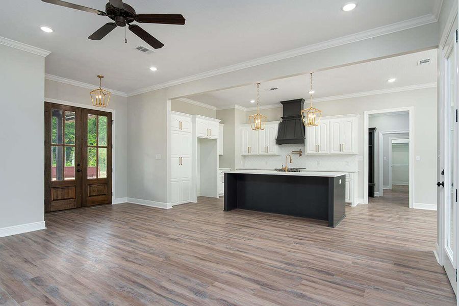 Kitchen with a kitchen island with sink, light countertops, wood finished floors, and premium range hood