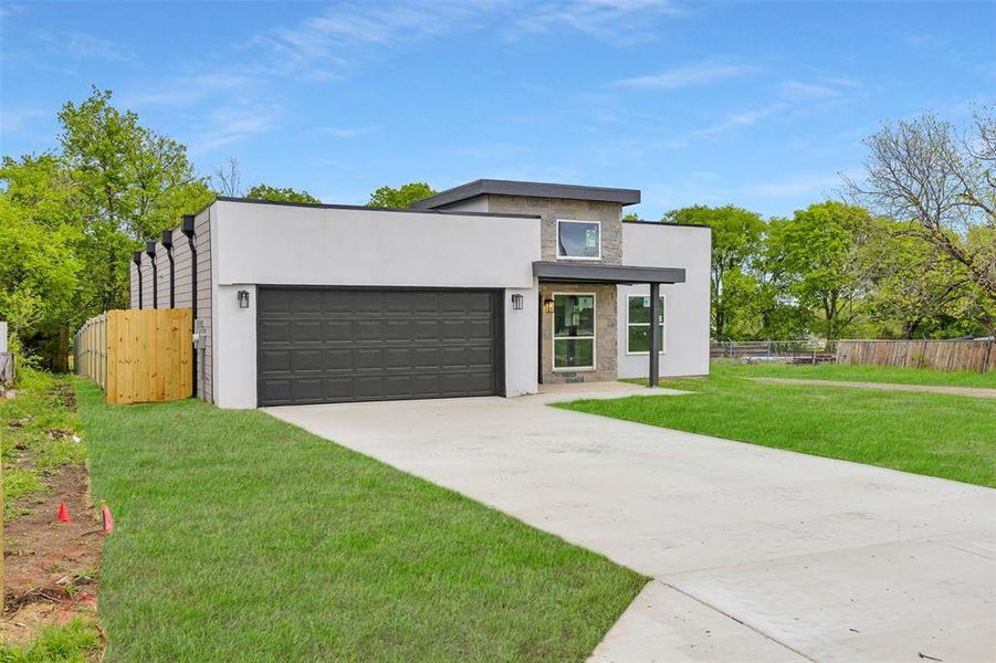 Contemporary house with a garage, stucco siding, a front yard, fence, and driveway Contemporary house with a garage, stucco siding, a front yard, fence, and driveway