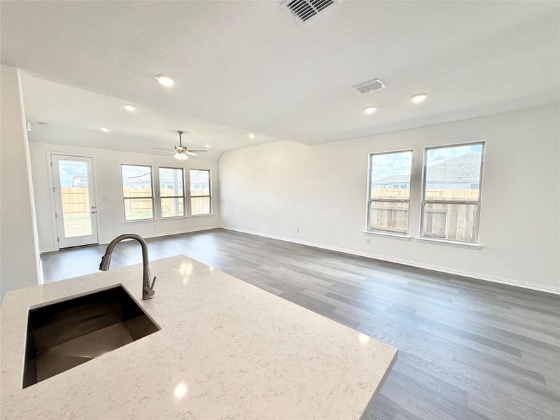 Kitchen featuring wood finished floors, plenty of natural light, light stone countertops, and recessed lighting Kitchen featuring wood finished floors, plenty of natural light, light stone countertops, and recessed lighting