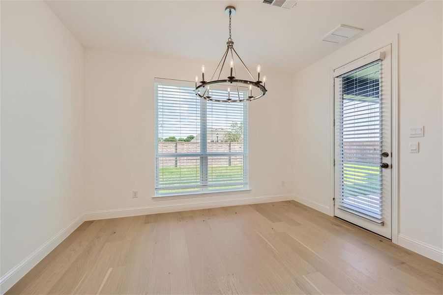 Empty room featuring a chandelier and light hardwood / wood-style floors