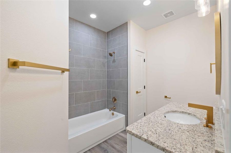 Full bath featuring washtub / shower combination, vanity, light wood finished floors, and recessed lighting Full bath featuring washtub / shower combination, vanity, light wood finished floors, and recessed lighting