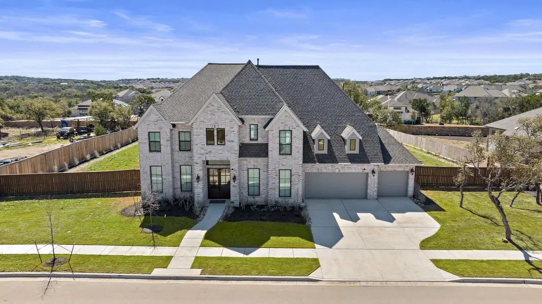 French country home featuring driveway, fence private yard, a front lawn, and brick siding