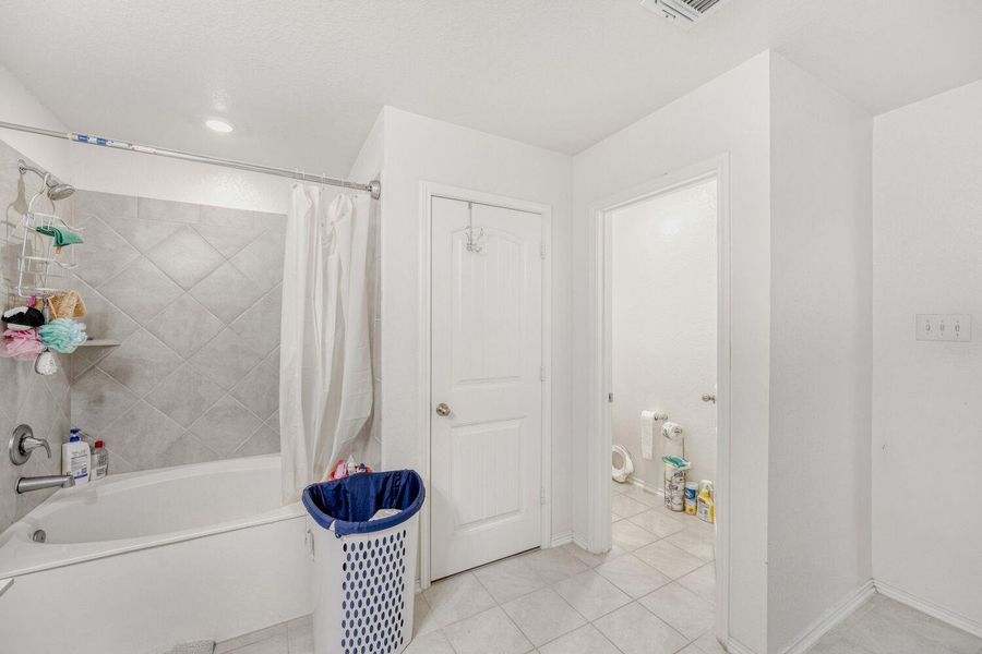 Full bathroom with shower / tub combo with curtain and light tile patterned flooring