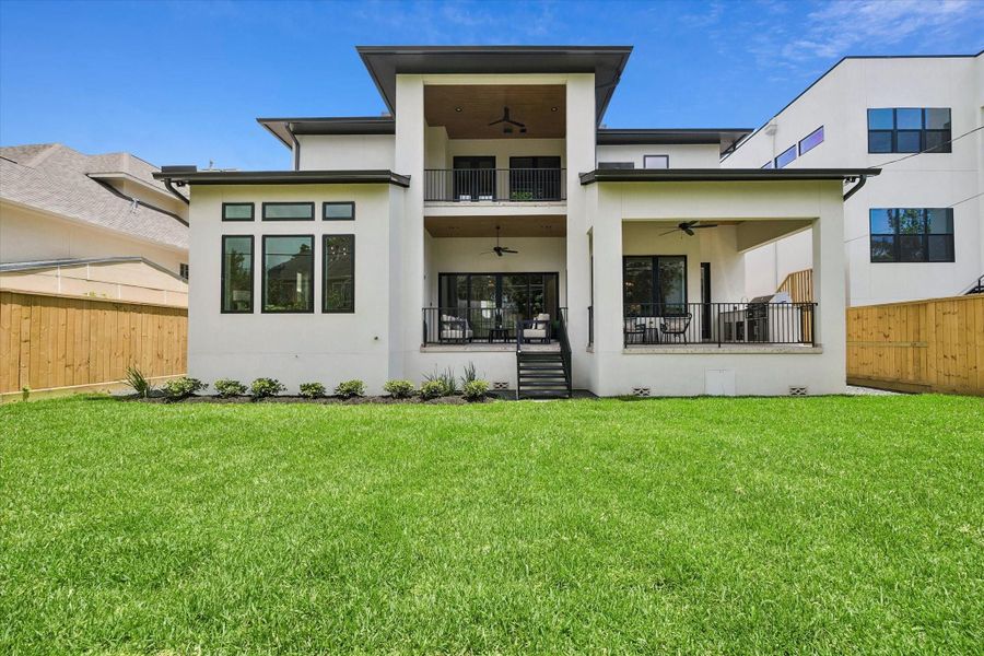 A straight-on view of the rear exterior highlights the home’s crisp white exterior, covered patio, balcony, and thoughtful connection to the backyard. A straight-on view of the rear exterior highlights the home’s crisp white exterior, covered patio, balcony, and thoughtful connection to the backyard.