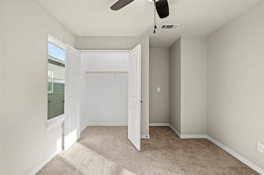 Unfurnished bedroom featuring light colored carpet, ceiling fan, and a closet