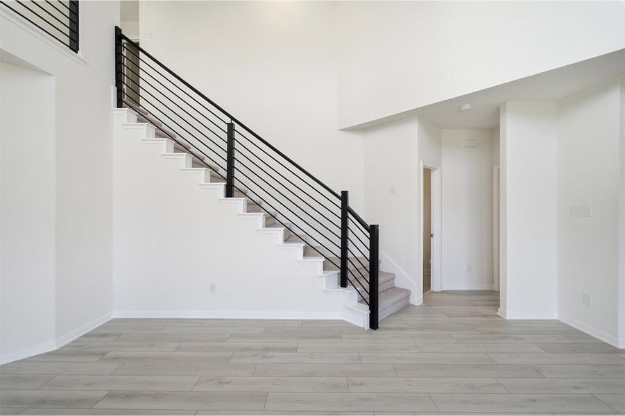 Contemporary staircase featuring black metal railings and light gray carpeted treads