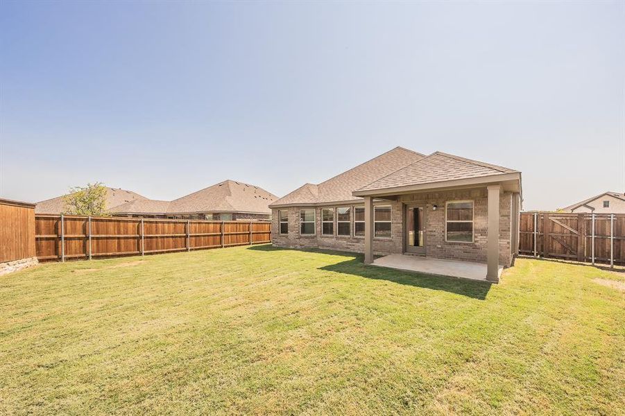 Back of property with a patio, a fenced backyard, a shingled roof, and brick siding Back of property with a patio, a fenced backyard, a shingled roof, and brick siding