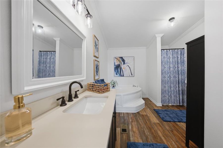 Bathroom featuring an integrated sink with a dark bronze faucet, a white countertop, and wood-finish flooring