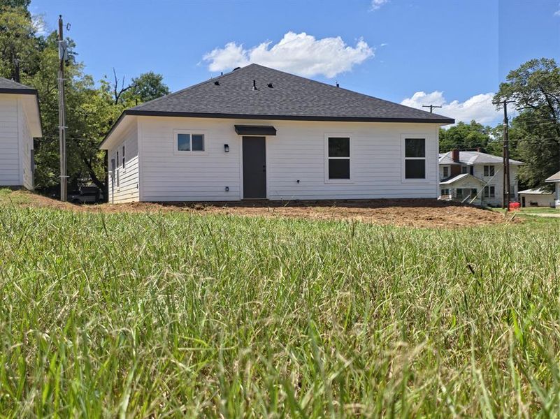 Back of house featuring a shingled roof Back of house featuring a shingled roof