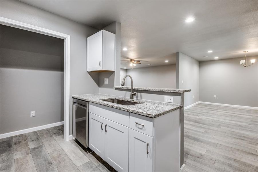 Kitchen with ceiling fan with notable chandelier, white cabinetry, light hardwood / wood-style floors, light stone counters, and decorative light fixtures