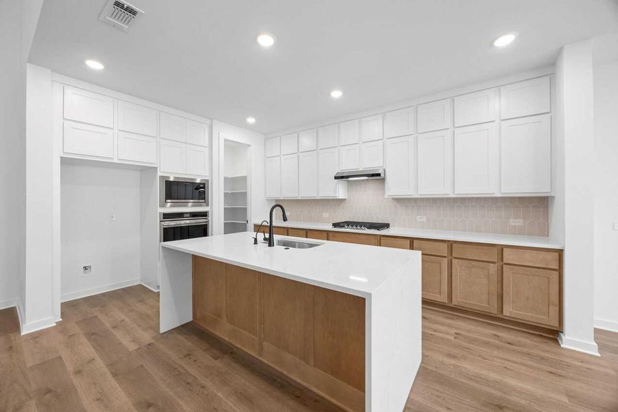 Kitchen featuring a kitchen island with sink, white cabinets, tasteful backsplash, recessed lighting, and light wood finished floors Kitchen featuring a kitchen island with sink, white cabinets, tasteful backsplash, recessed lighting, and light wood finished floors