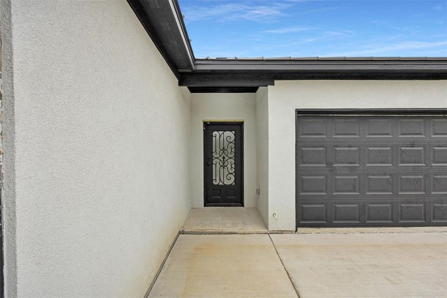 View of exterior entry featuring stucco siding and driveway