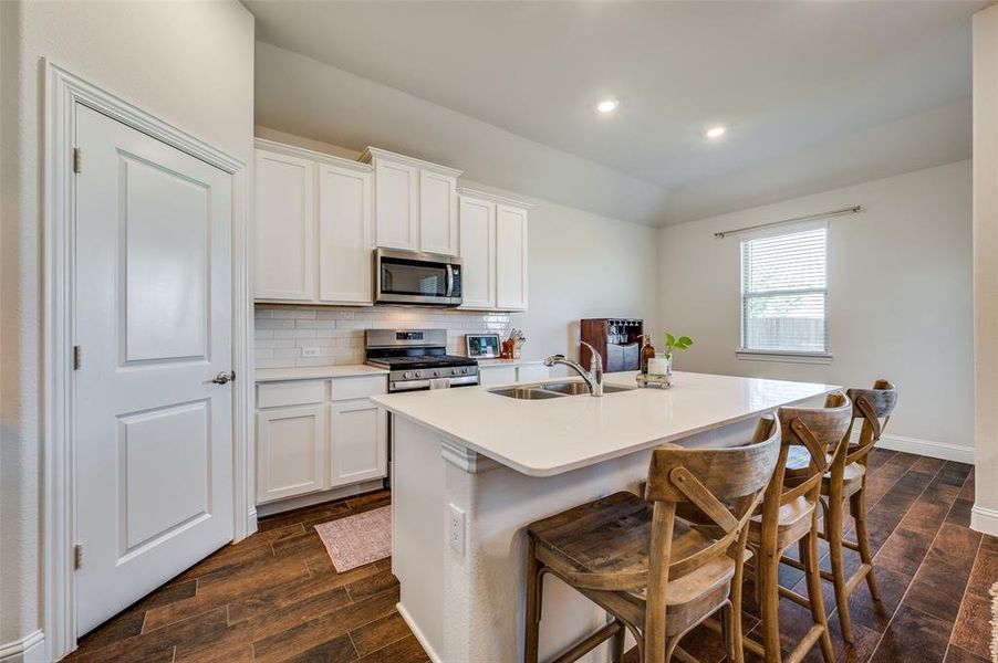 Kitchen with a kitchen island with sink, white cabinetry, nice sized pantry