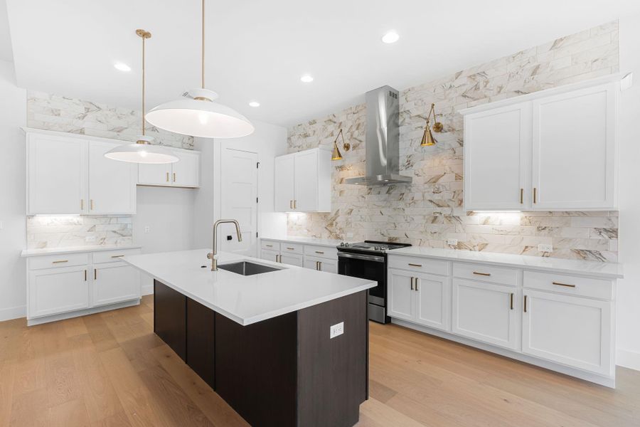 Kitchen featuring sink, white cabinetry, decorative light fixtures, stainless steel electric range, and wall chimney range hood Kitchen featuring sink, white cabinetry, decorative light fixtures, stainless steel electric range, and wall chimney range hood