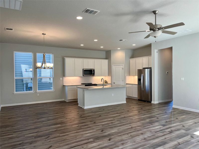 Kitchen featuring open floor plan, white cabinets, appliances with stainless steel finishes, a chandelier, and recessed lighting
