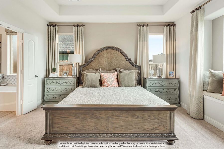 Master bedroom with wood bed frame, tray ceiling, carpet floors, and ensuite bathroom door visible