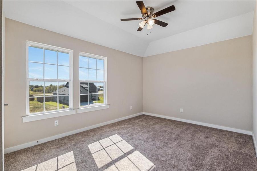 Bedroom with ceiling fan, light colored carpet, and vaulted ceiling Bedroom with ceiling fan, light colored carpet, and vaulted ceiling
