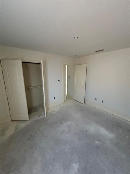 Unfurnished bedroom with unfinished concrete floors and a closet
