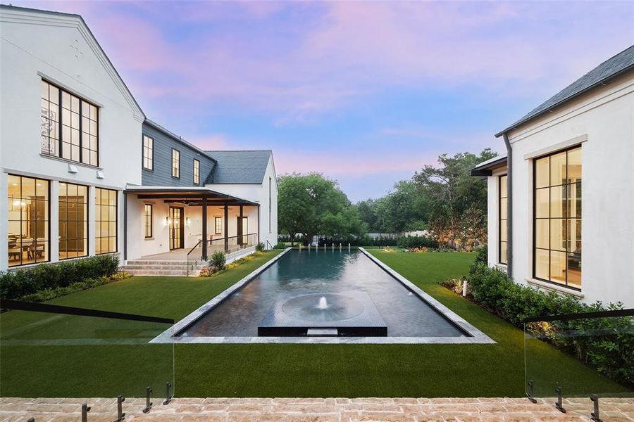 Infinity edge pool and spa with turfed yard and outdoor kitchen