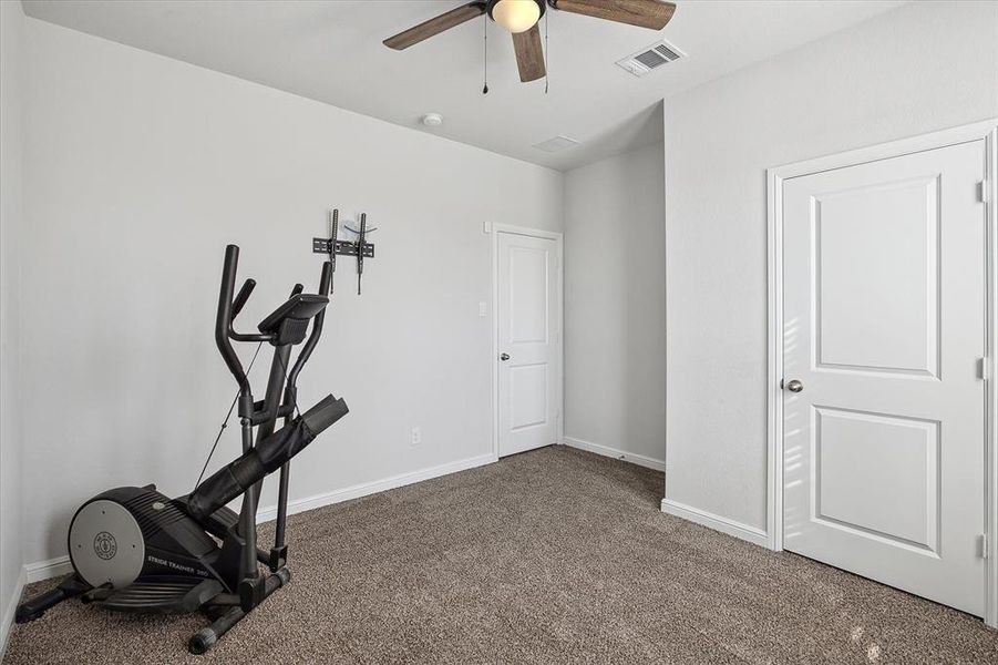 Workout area with ceiling fan and dark carpet Workout area with ceiling fan and dark carpet