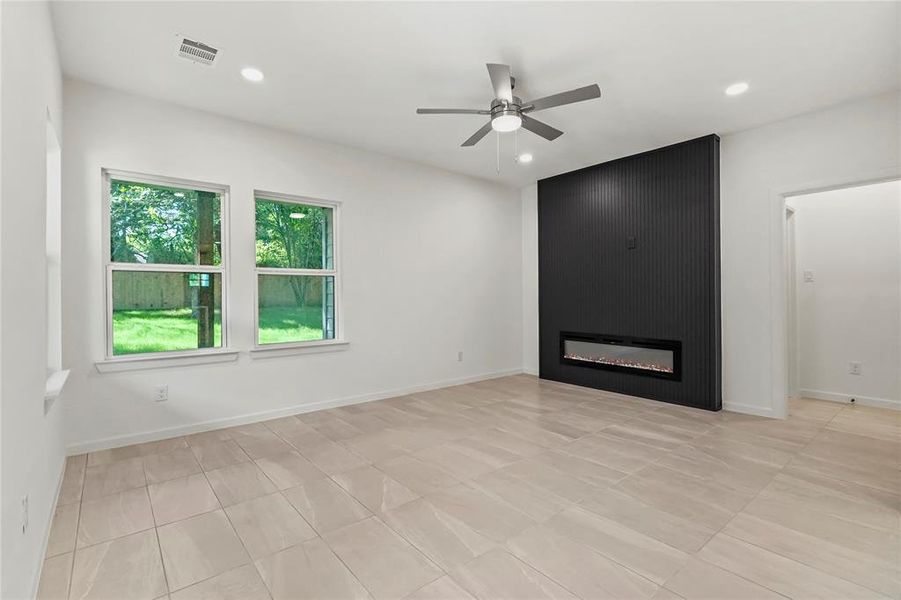 Unfurnished living room featuring ceiling fan, a fireplace, recessed lighting, and light tile patterned floors