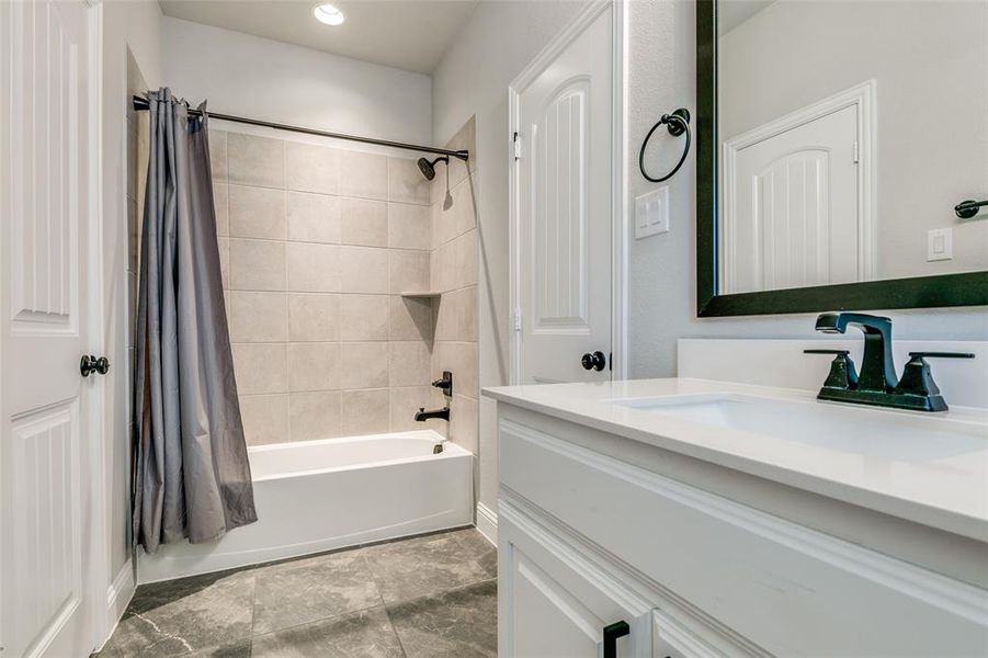 Bathroom with shower / bathtub combination with curtain, vanity, and tile floors