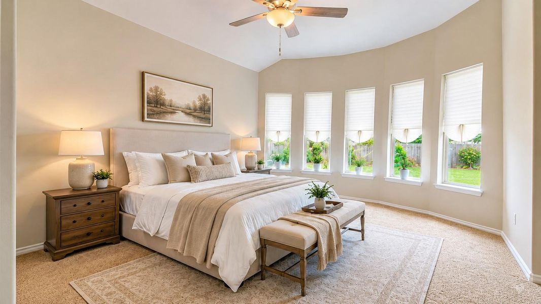 This Primary Bedroom features an angled ceiling with a ceiling fan and a curved accent wall with five large windows. The flooring consists of neutral-toned carpeting throughout the space.**This room has been virtually staged.