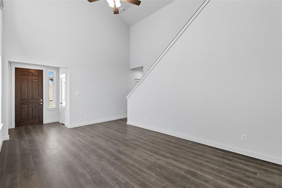 Entryway with high vaulted ceiling, dark wood-type flooring, ceiling fan, and stairs Entryway with high vaulted ceiling, dark wood-type flooring, ceiling fan, and stairs