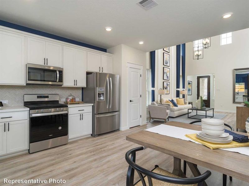 Kitchen with stainless steel appliances, white cabinetry, tasteful backsplash, light wood-style flooring, and recessed lighting