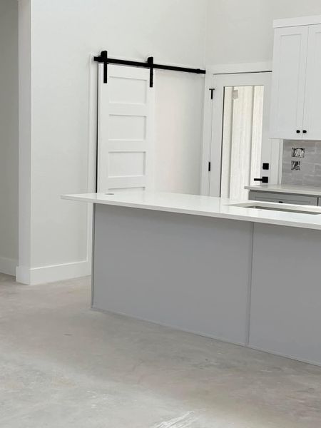 Kitchen featuring white cabinetry, light countertops, a barn door, and concrete flooring