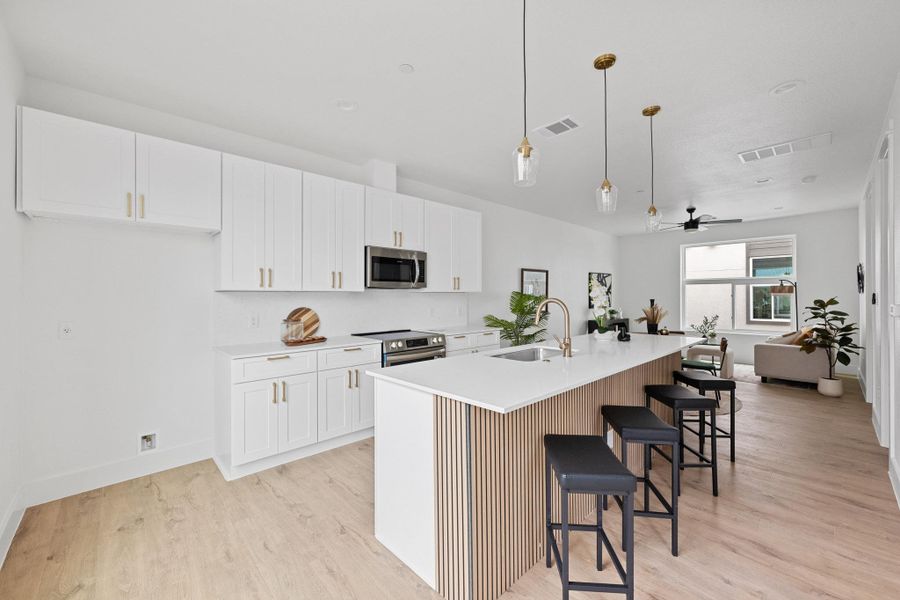 Modern kitchen featuring white shaker cabinetry, stainless steel appliances, a white quartz countertop, and a full-height tile backsplash