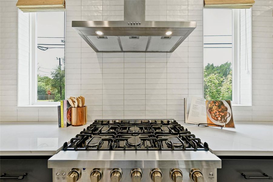 6-burner gas range with stainless hood and floor-to-ceiling stacked tile backsplash. 6-burner gas range with stainless hood and floor-to-ceiling stacked tile backsplash.