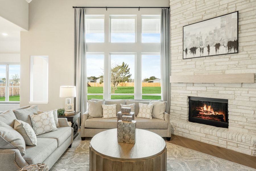 Living room with tall windows, stone fireplace, and neutral sofas on hardwood floors Living room with tall windows, stone fireplace, and neutral sofas on hardwood floors