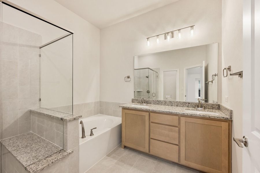 Bathroom with double sink vanity, granite countertop, soaking tub, and glass shower enclosure Bathroom with double sink vanity, granite countertop, soaking tub, and glass shower enclosure
