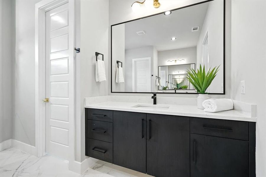 Bathroom with vanity, light marble finish floors, and recessed lighting