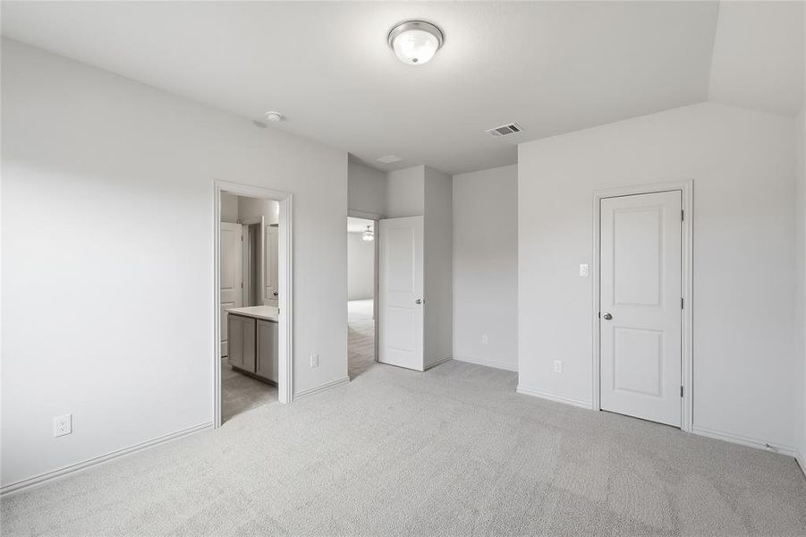 Unfurnished bedroom with light colored carpet and connected bathroom