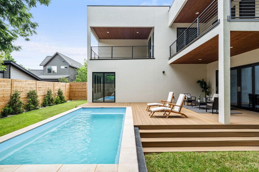 A modern outdoor living space features a sparkling pool alongside a spacious multi-level wooden deck and private yard. A modern outdoor living space features a sparkling pool alongside a spacious multi-level wooden deck and private yard.