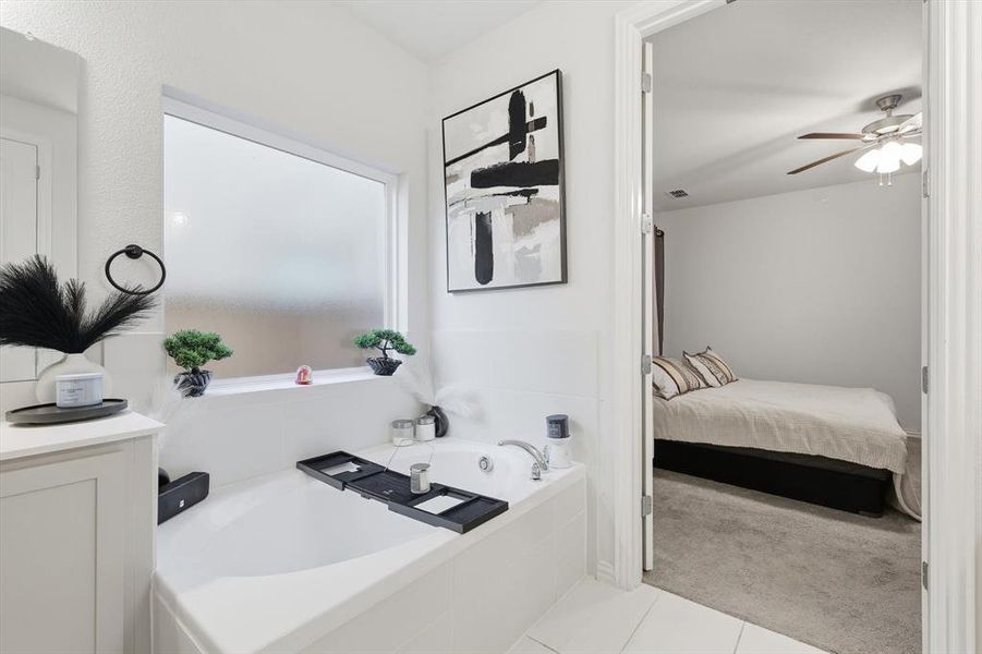 Bathroom with a bath, light carpet, light tile patterned floors, ensuite bath, and a ceiling fan