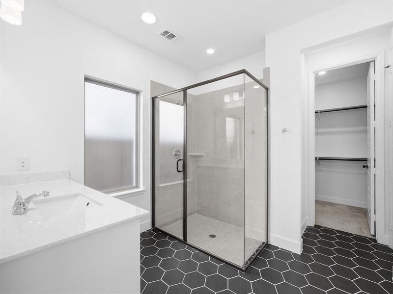 Primary bath featuring vanity, a shower stall, a spacious closet, recessed lighting, and dark tile patterned flooring Primary bath featuring vanity, a shower stall, a spacious closet, recessed lighting, and dark tile patterned flooring