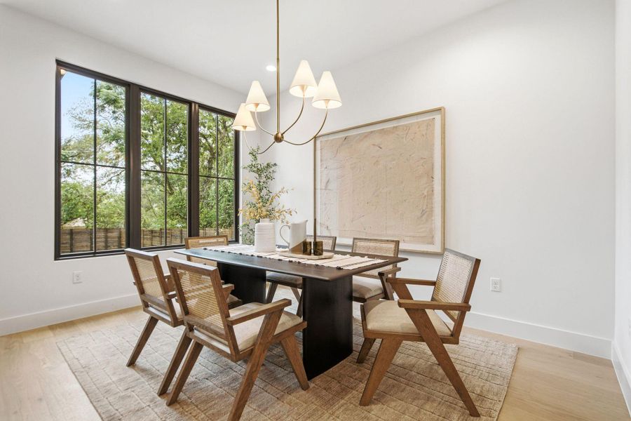 Large multi-pane windows bring natural light and views of mature trees into the dining space.