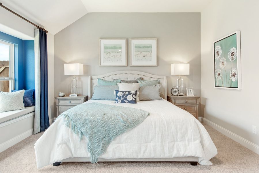 Bedroom with vaulted ceiling, king bed, neutral carpet, window seat, and blue accent wall