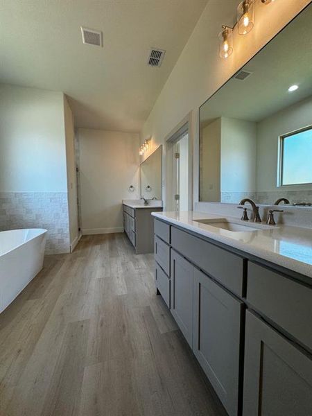 Bathroom with wood-type flooring, a bathing tub, and vanity