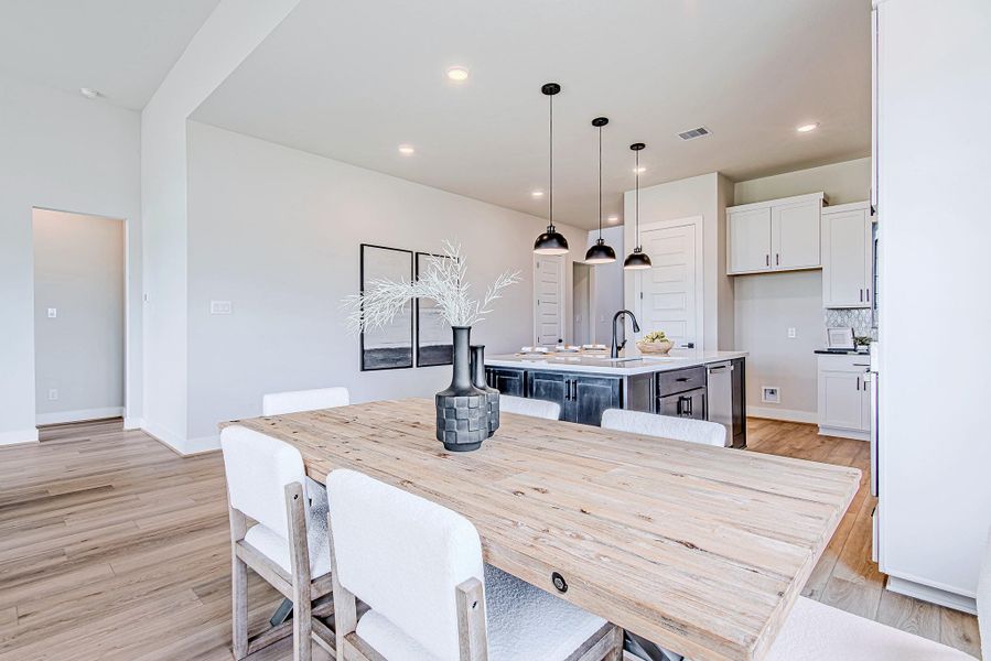 The dining area offers a seamless connection to the kitchen and island bar seating, all wrapped in soft light from the oversized windows.