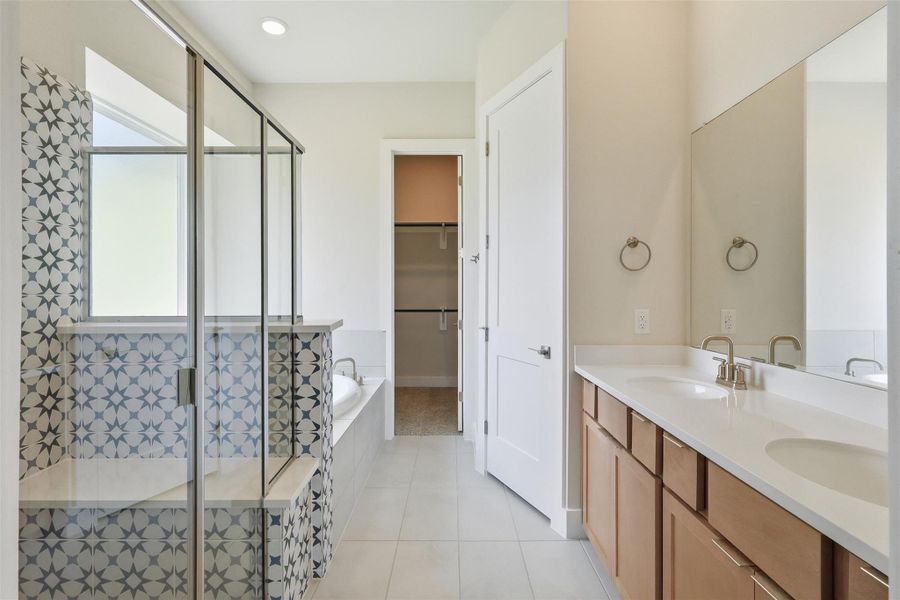 The primary bath features dual vanities, designer tile, a soaking tub, and a glass-enclosed shower—balancing statement style with everyday function.