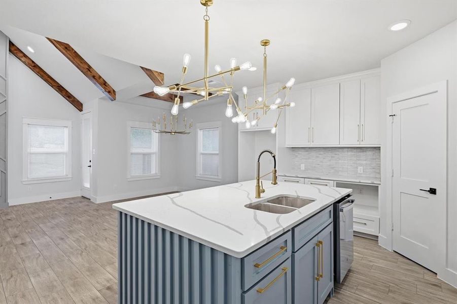 Kitchen with backsplash, white cabinets, pendant lighting, light wood-style floors, and an island with sink