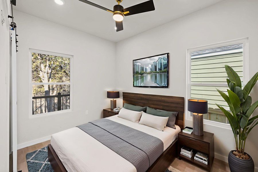 Bedroom featuring multiple windows, wood finished floors, and ceiling fan Bedroom featuring multiple windows, wood finished floors, and ceiling fan
