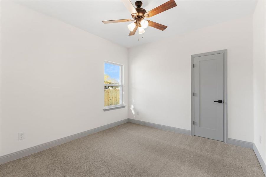 Carpeted empty room featuring baseboards and ceiling fan